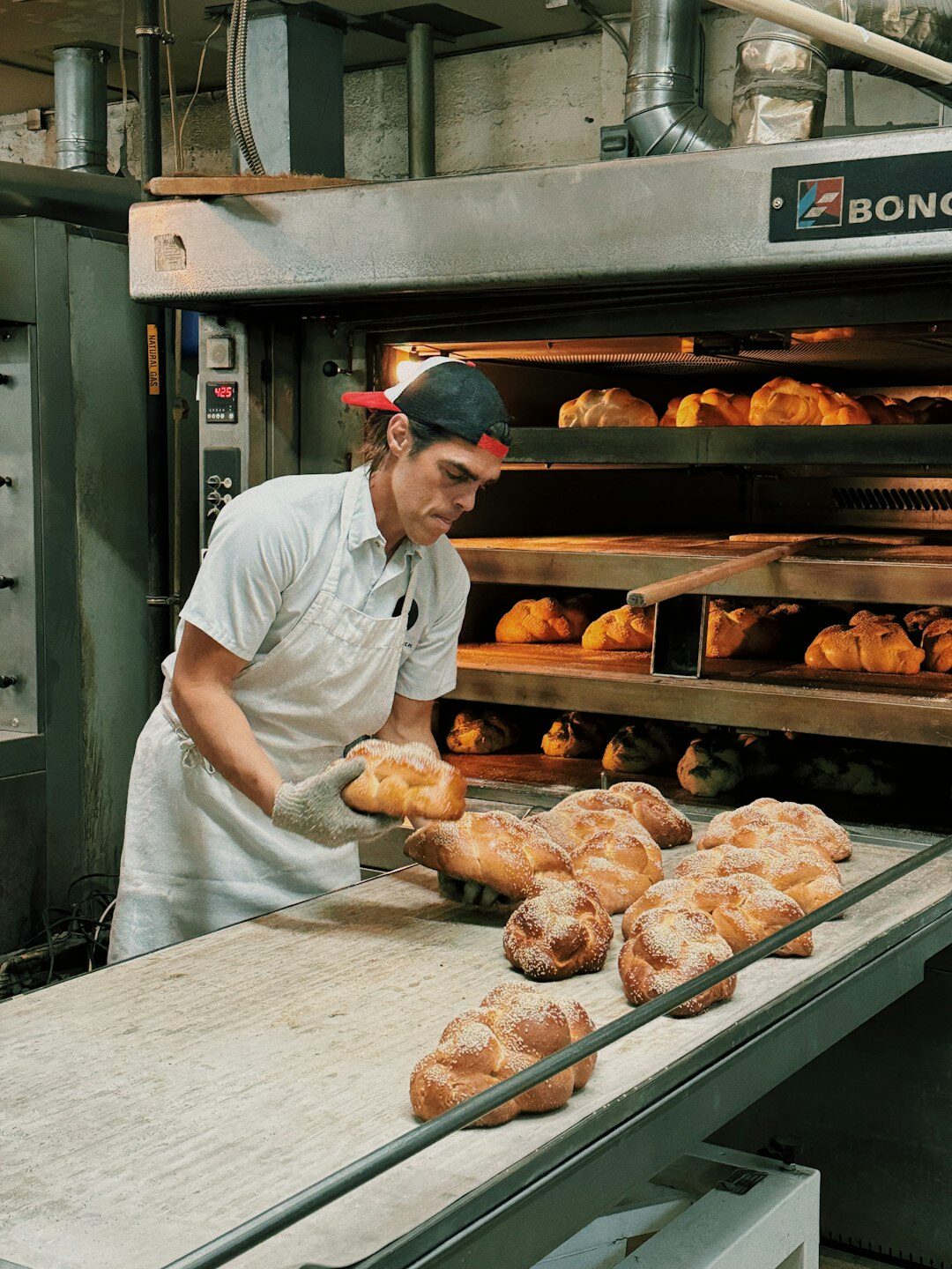 Danish baker taking fresh bread out of the oven